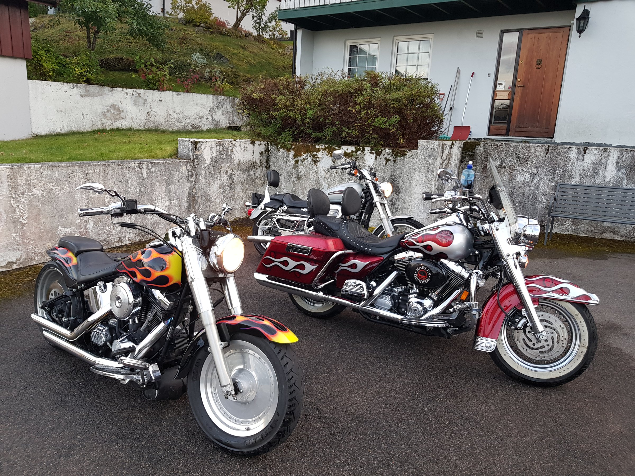Tre Harley-Davidson motorsykler parkert utenfor et hus